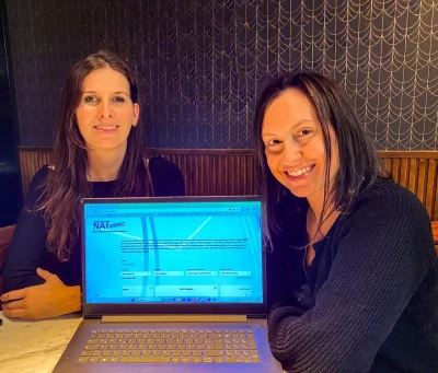 Two people in front of a laptop, the database is visible