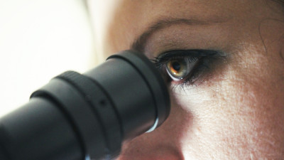 A woman looks through a microscope