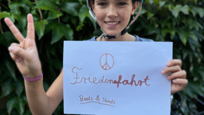 A child holds up a poster with the word “Peace Ride” on it