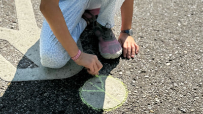 A child draws a peace sign with chalk