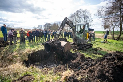 A group of people stand around an excavator at the symbolic ground-breaking ceremony